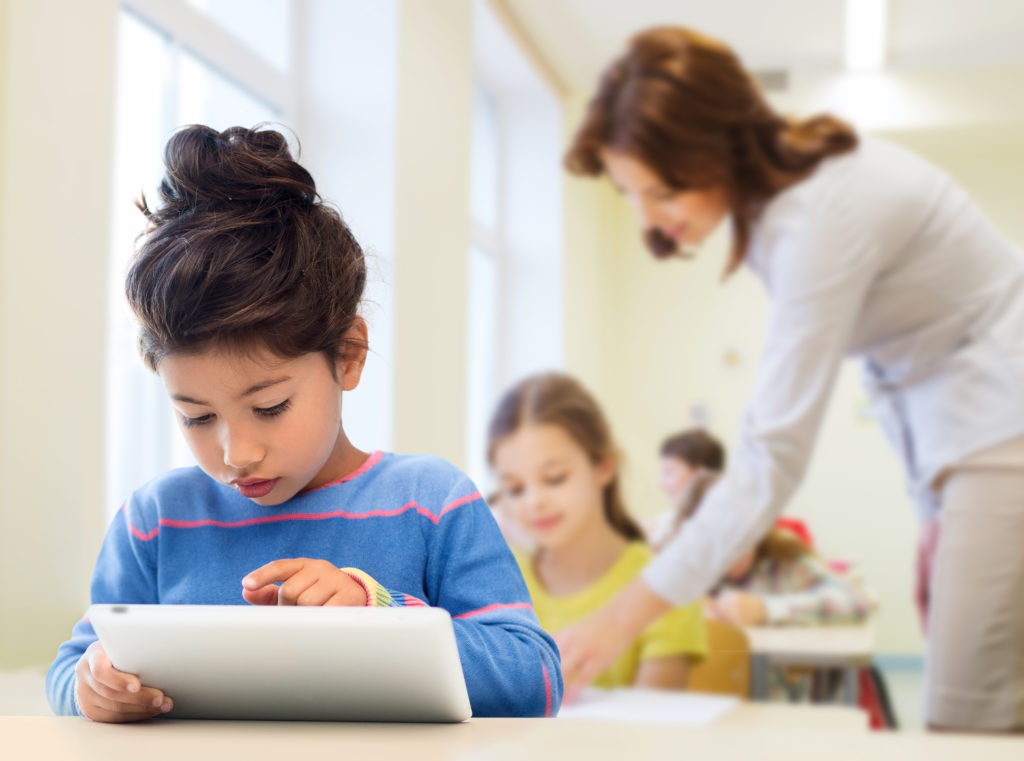 little school girl with tablet pc over classroom