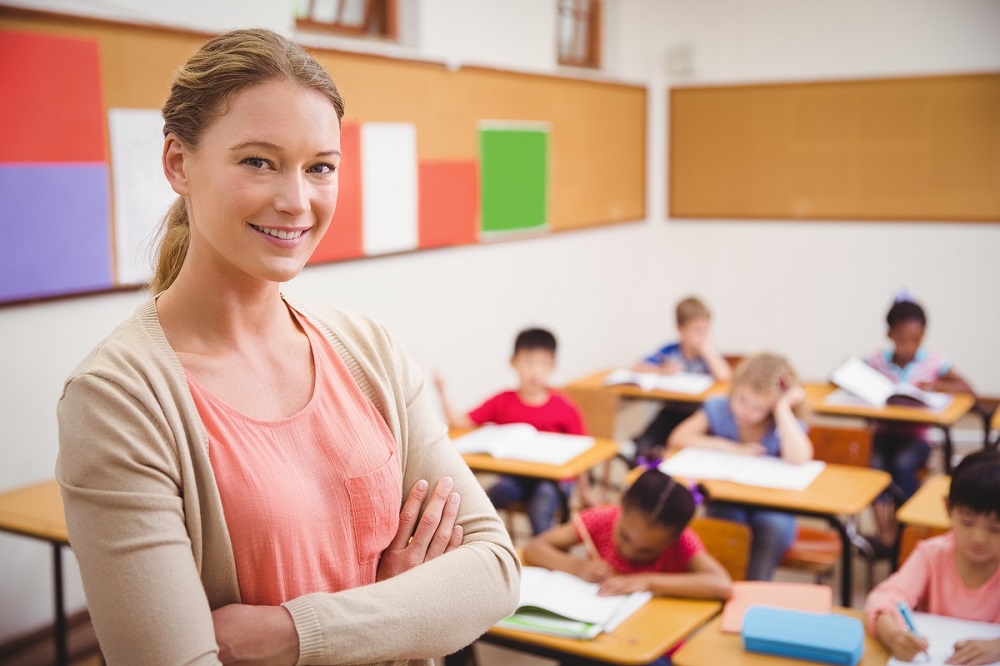 Pretty teacher smiling at camera at top of classroom