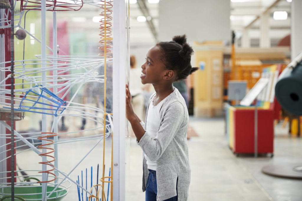 Young black girl looking at a science exhibit, close up