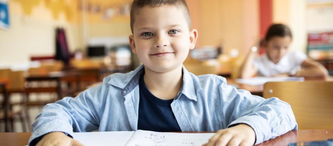 Portrait of young boy in primary school classroom.He sitting at