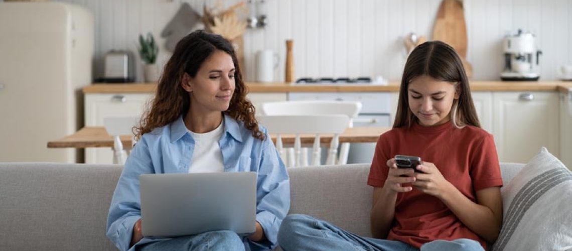 Parental monitoring of adolescents. Curious mother spying teenage daughter looking child text messages on smartphone. Mom and kid using gadgets, resting on sofa at home. Family and modern technologies